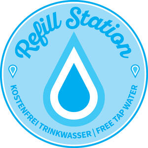 In einem hellblauen Kreis ist ein großer dunkelblauer Tropfen zu sehen. Das Logo weist darauf hin, dass es an dieser Stelle kostenfreies Trinkwasser gibt.