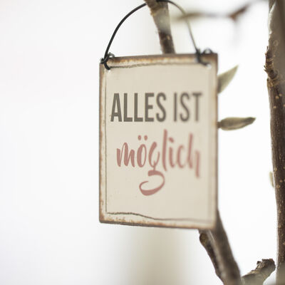 Ein Schild mit der Aufschrift "Alles ist möglich" hängt an einem Zweig.