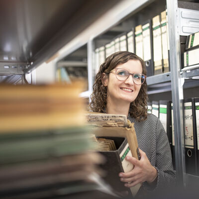 Eine Mitarbeiterin im Archiv des Kreises inmitten von Regalen mit Ordnern und Kartons.